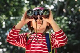 Preschool child looking through binoculars watching for birds