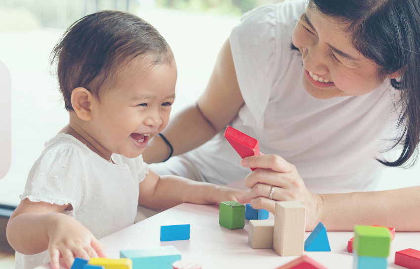 Mother interacting with baby as she practices serve and return interaction while playing with blocks