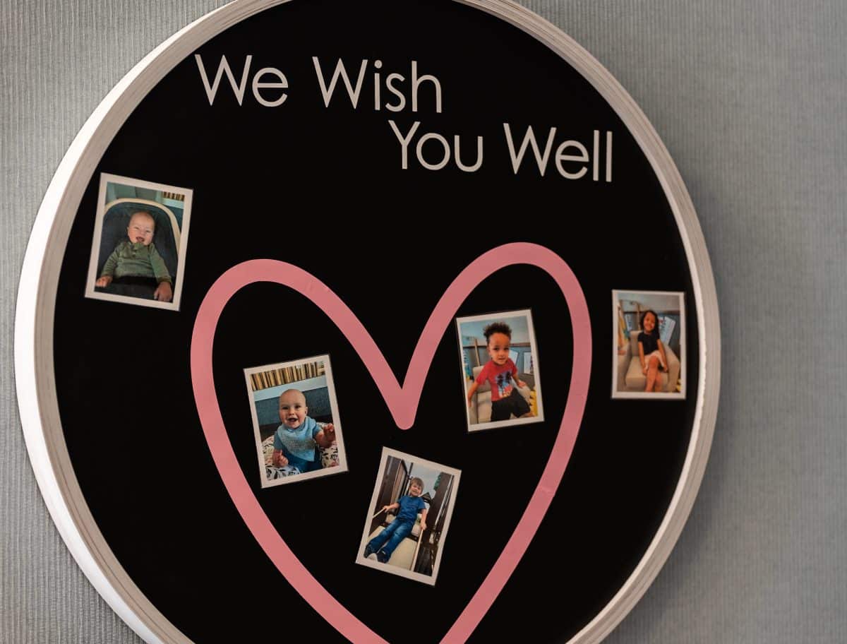 A circular board, with an outline of a pink heart and the words "We Wish You Well."