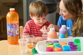 A preschool teacher helps a young child with an art project.