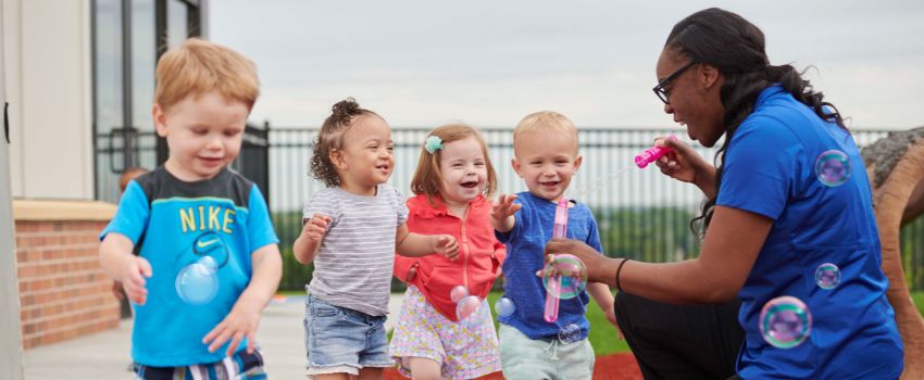 Older infant children exploring bubbles outside at New Horizon Academy