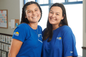 Two teachers stand together smiling